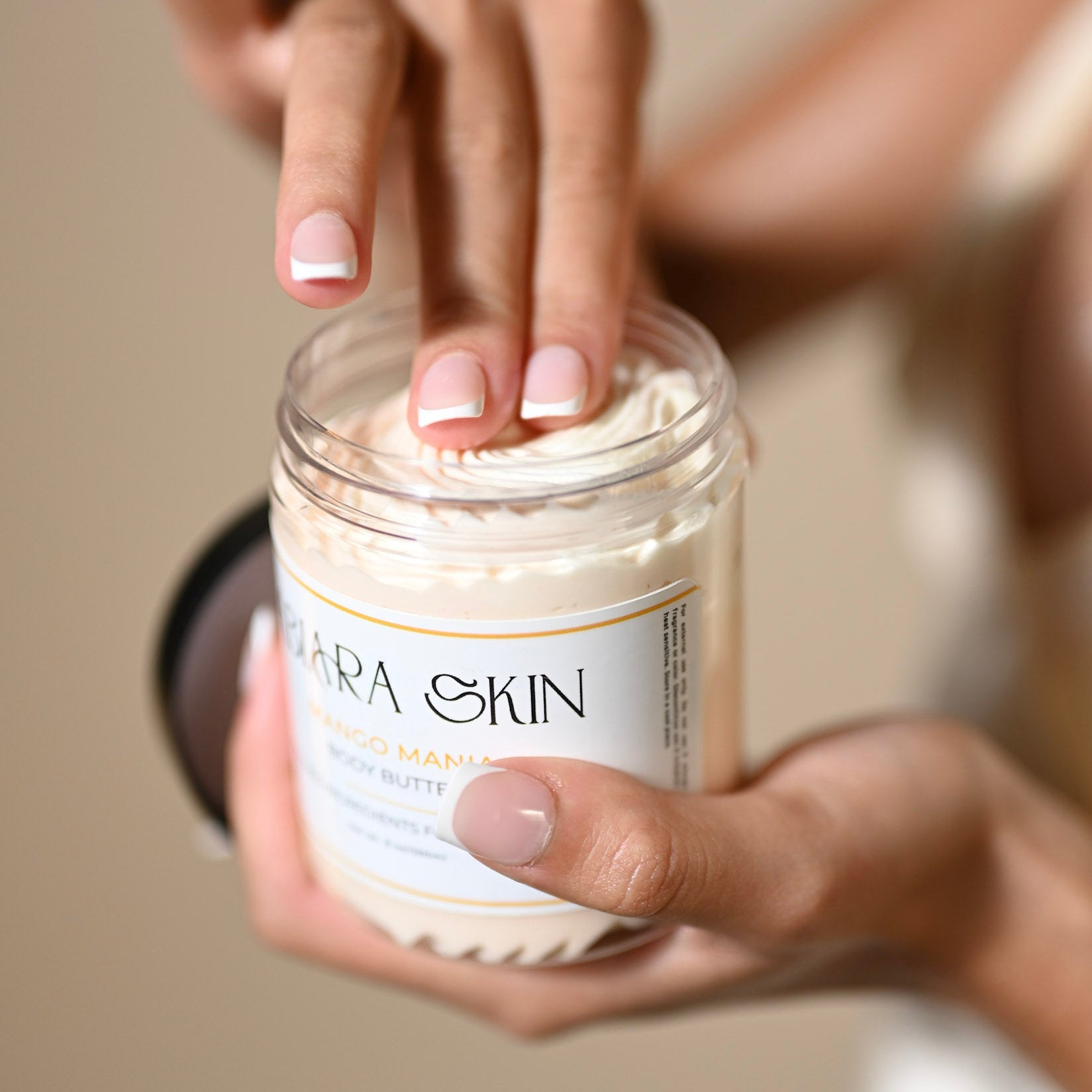 Jar of Body Butter by Abiara Skin held by a hand with a blurred background